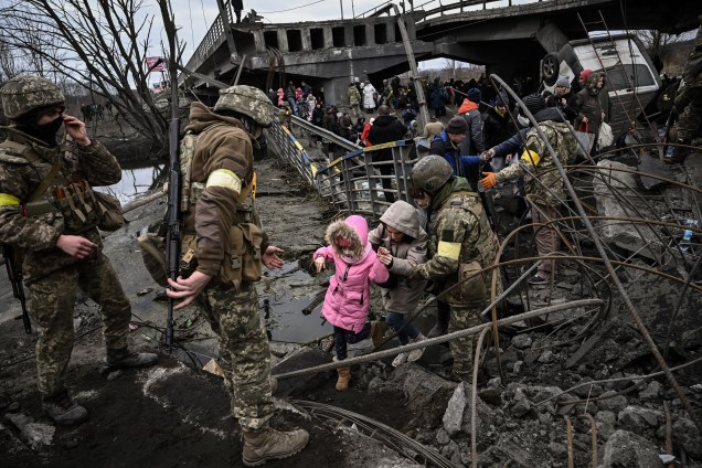 Pessoas atravessam uma ponte destruída ao evacuar a cidade de Irpin, ao noroeste de Kiev -