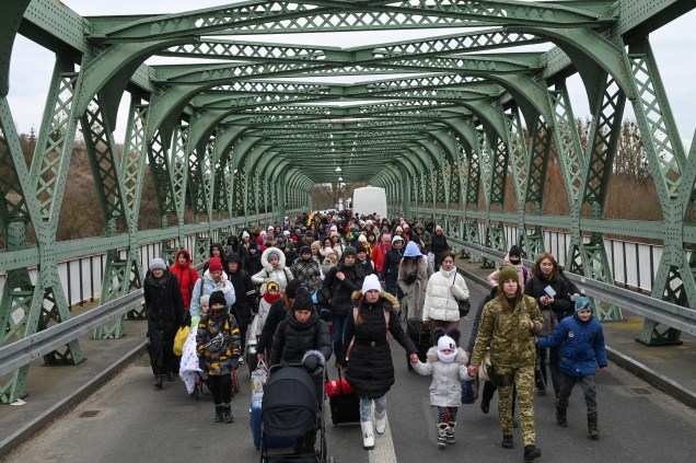 Refugiados ucranianos caminham por uma ponte na fronteira com a Polônia, em Zosin-Ustyluh, no oeste da Ucrânia -