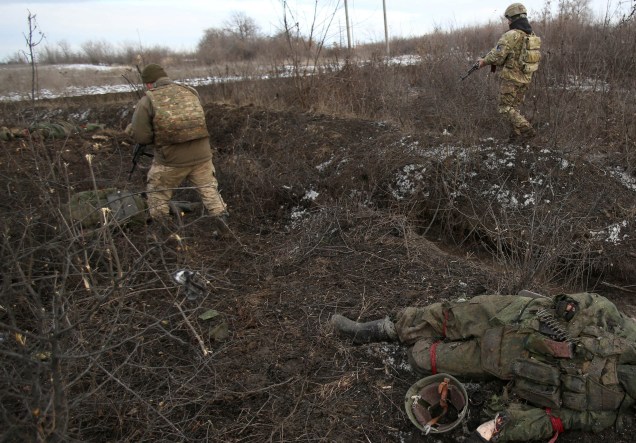 Soldado das Forças Militares Ucranianas passam por um corpo, após combates contra tropas russas e separatistas apoiados pela Rússia perto da vila de Zolote, na região de Lugansk -