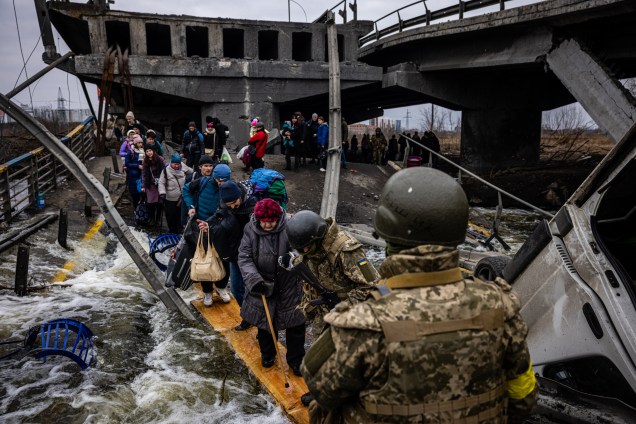 Ucranianos atravessam uma ponte destruída enquanto fogem da cidade de Irpin -
