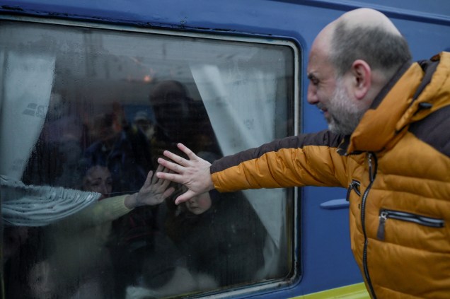 Um pai chora ao se despedir de sua família em frente a um trem de evacuação na estação central de trem de Odessa -