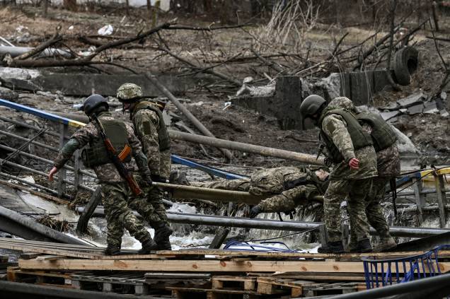 Militares ucranianos carregam o corpo de um companheiro em uma maca na cidade de Irpin -