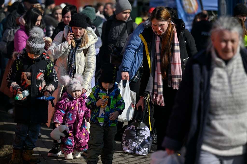 Refugees from Ukraine arrive to take further transport after crossing the Ukrainian border with Poland, at the Medyka border crossing, southeastern Poland, on March 13, 2022. - The number of refugees fleeing Ukraine since the Russian invasion two weeks ago is now nearly 2.6 million, the UN said on March 12, 2022. (Photo by Louisa GOULIAMAKI / AFP)