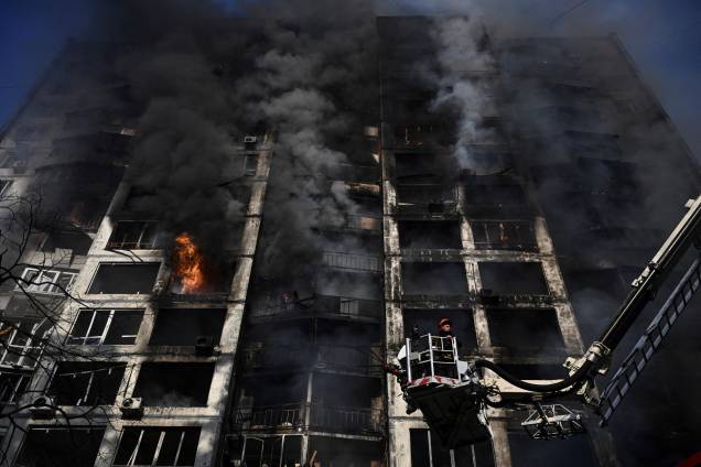Bombeiros trabalhando para apagar um incêndio que eclodiu em um prédio de apartamentos atingido por um bombardeio em Kiev -