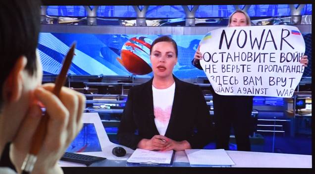 Um funcionário dissidente russo do Channel One entrar no estúdio de TV Ostankino durante o noticiário noturno mais assistido da Rússia, segurando um pôster que diz "Sem Guerra" e condenando a ação militar de Moscou na Ucrânia em Moscou