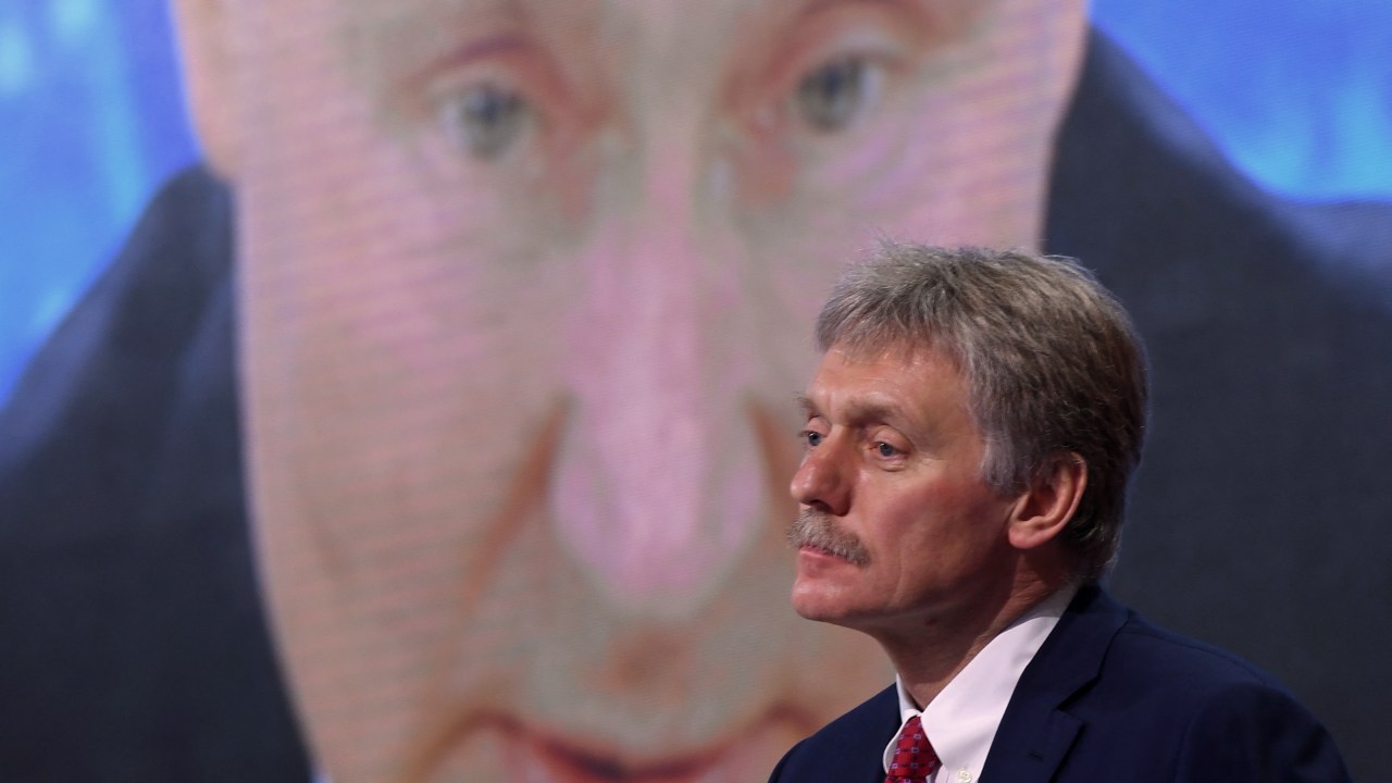 Porta-voz do Kremlin, Dmitry Peskov, aparece em frente tela com imagem do presidente russo, Vladimir Putin (22/3/2022) //