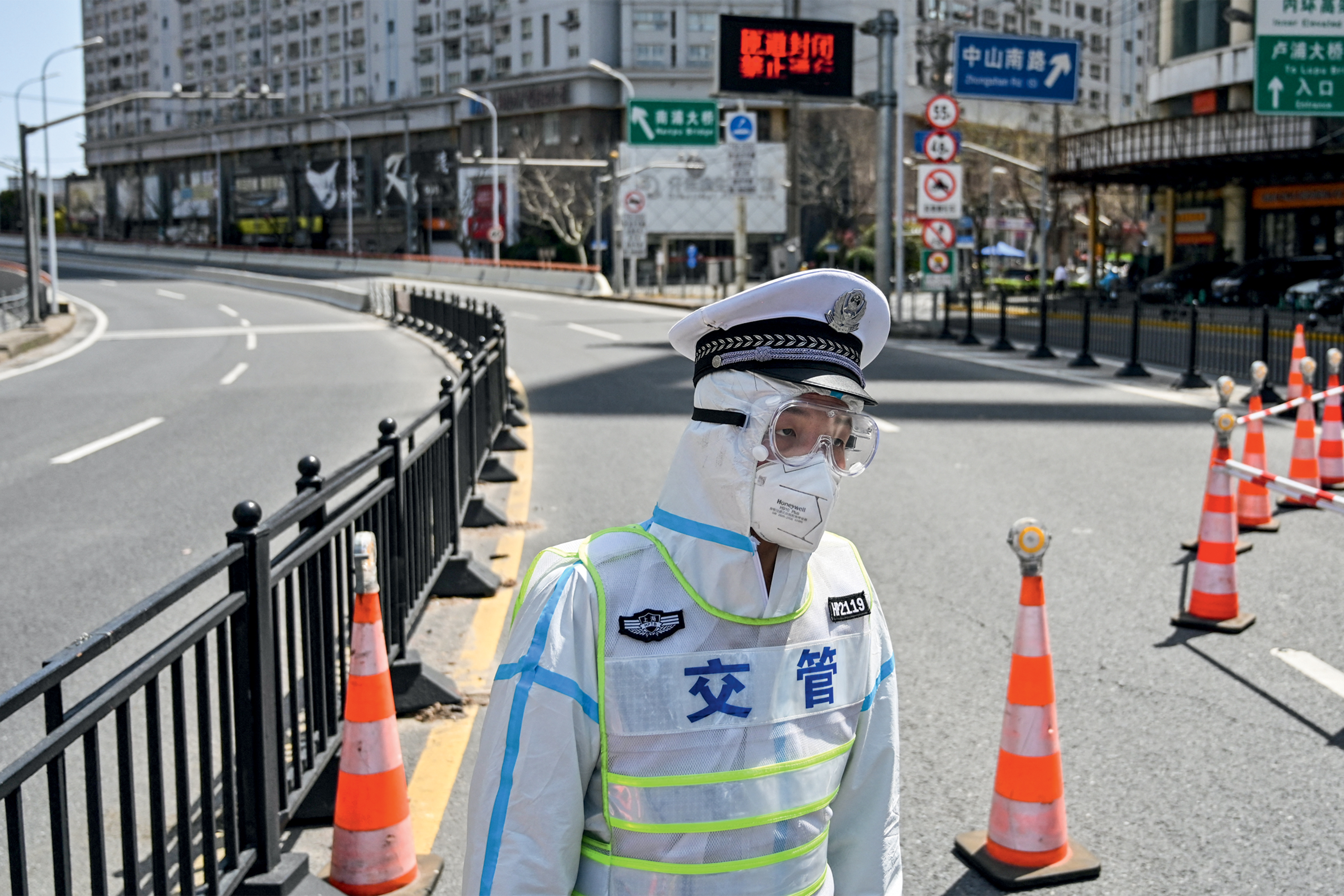 A transit officer, wearing a protective gear, controls access to a bridge in the direction of Pudong district in lockdown as a measure against the Covid-19 coronavirus, in Shanghai on March 29, 2022. (Photo by Hector RETAMAL / AFP)