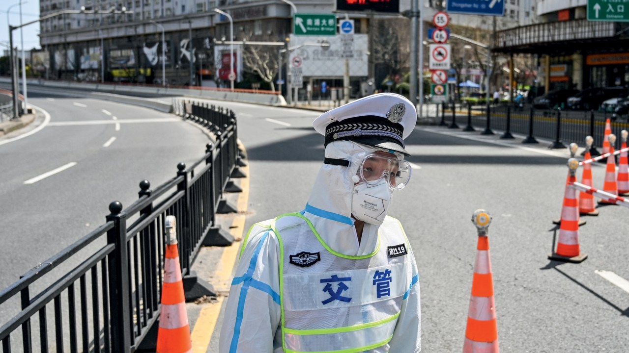 A transit officer, wearing a protective gear, controls access to a bridge in the direction of Pudong district in lockdown as a measure against the Covid-19 coronavirus, in Shanghai on March 29, 2022. (Photo by Hector RETAMAL / AFP)