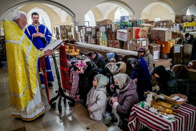 Membros da comunidade ucraniana durante um serviço pela paz na Ucrânia e vítimas de guerra em uma igreja católica ucraniana cheia de caixas de ajuda humanitária, em Berlim -