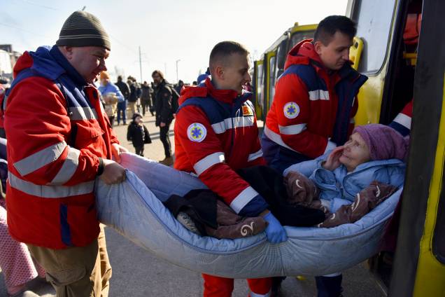 Médicos ajudam uma idosa depois que ela foi evacuada de uma vila próxima a Kiev, ocupada pelo exército russo -