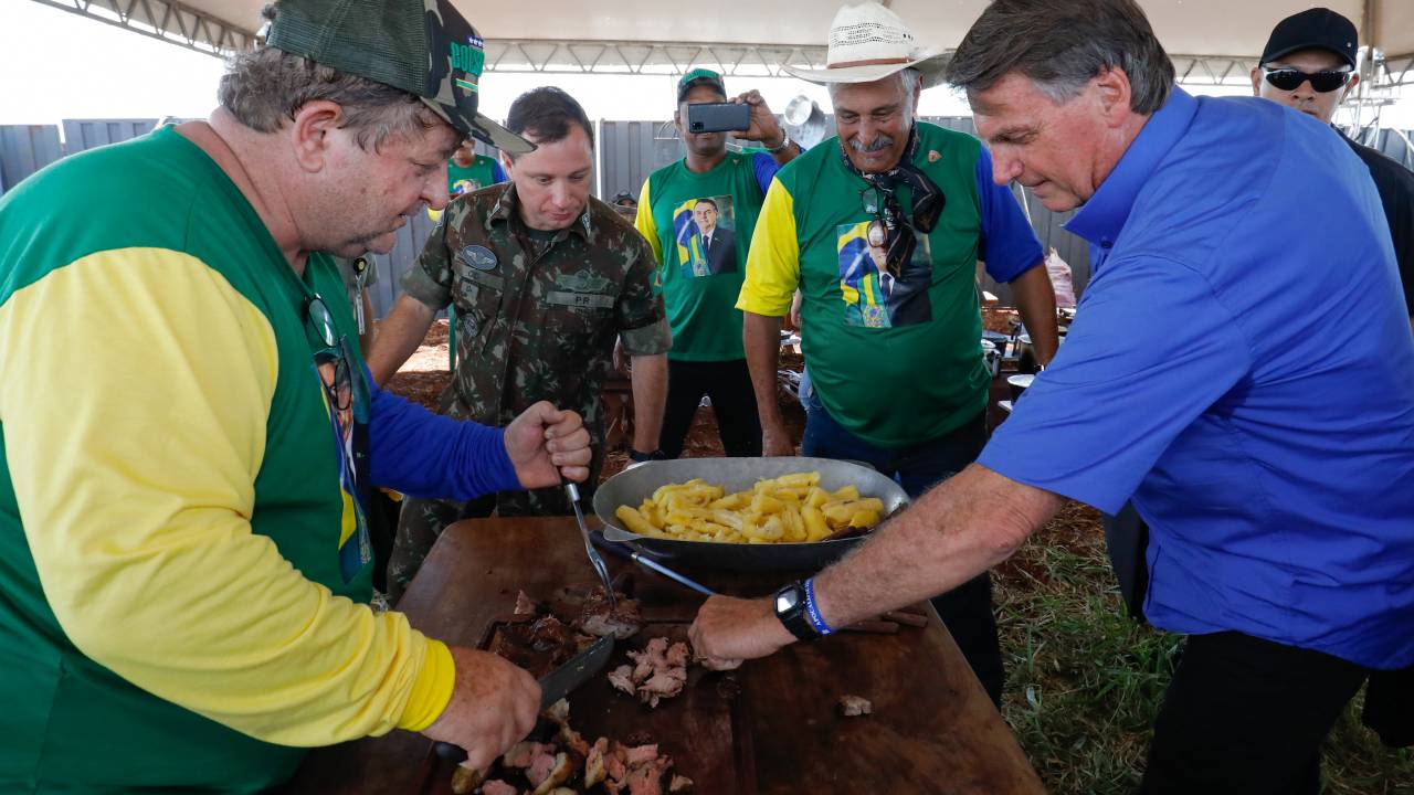 O presidente Jair Bolsonaro pega um pedaço de carne durante viagem a Ponta Porã (MS), na terça-feira passada