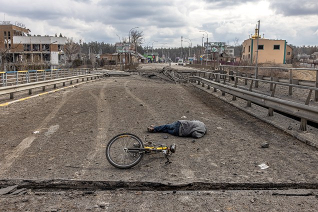 O corpo de um homem morto é visto em uma ponte destruída ao lado de carros abandonados, em Irpin -