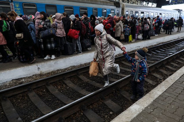 Uma mulher caminha com seu filho nos trilhos da estação de trem de Lviv -