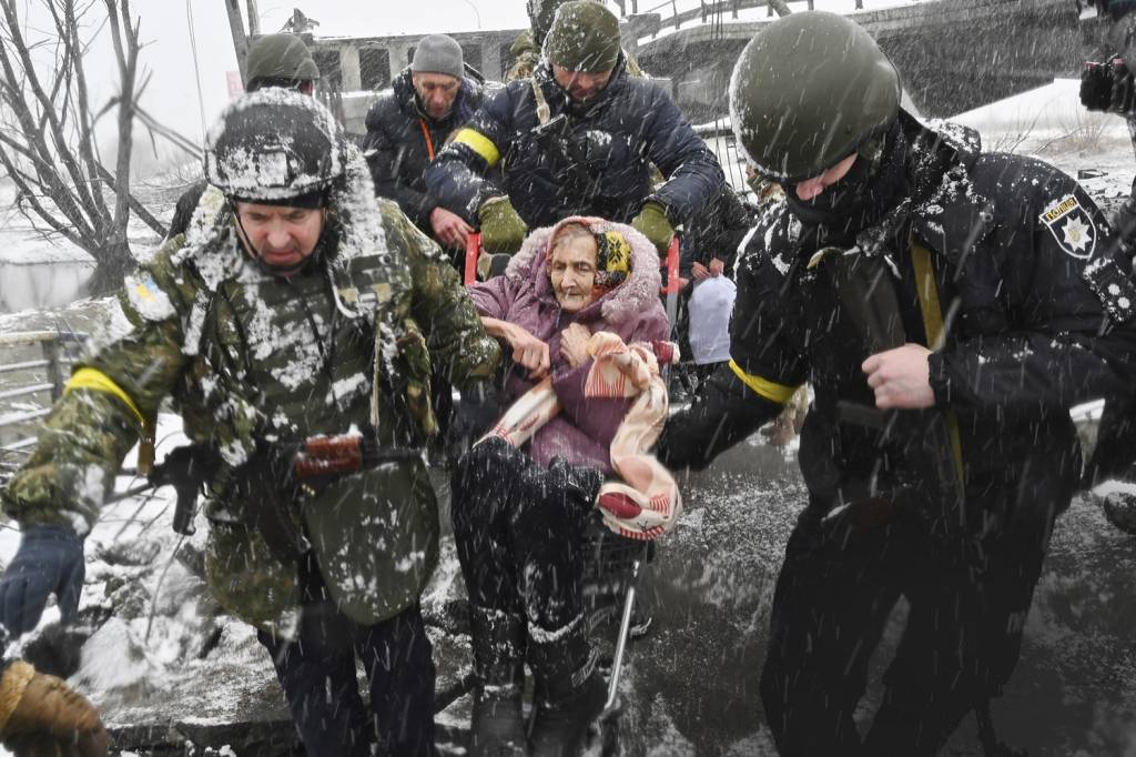 DIFICULDADE - Caminho cortado: sob a neve, soldados ajudam idosa em fuga a se desviar de ponte que desabou -