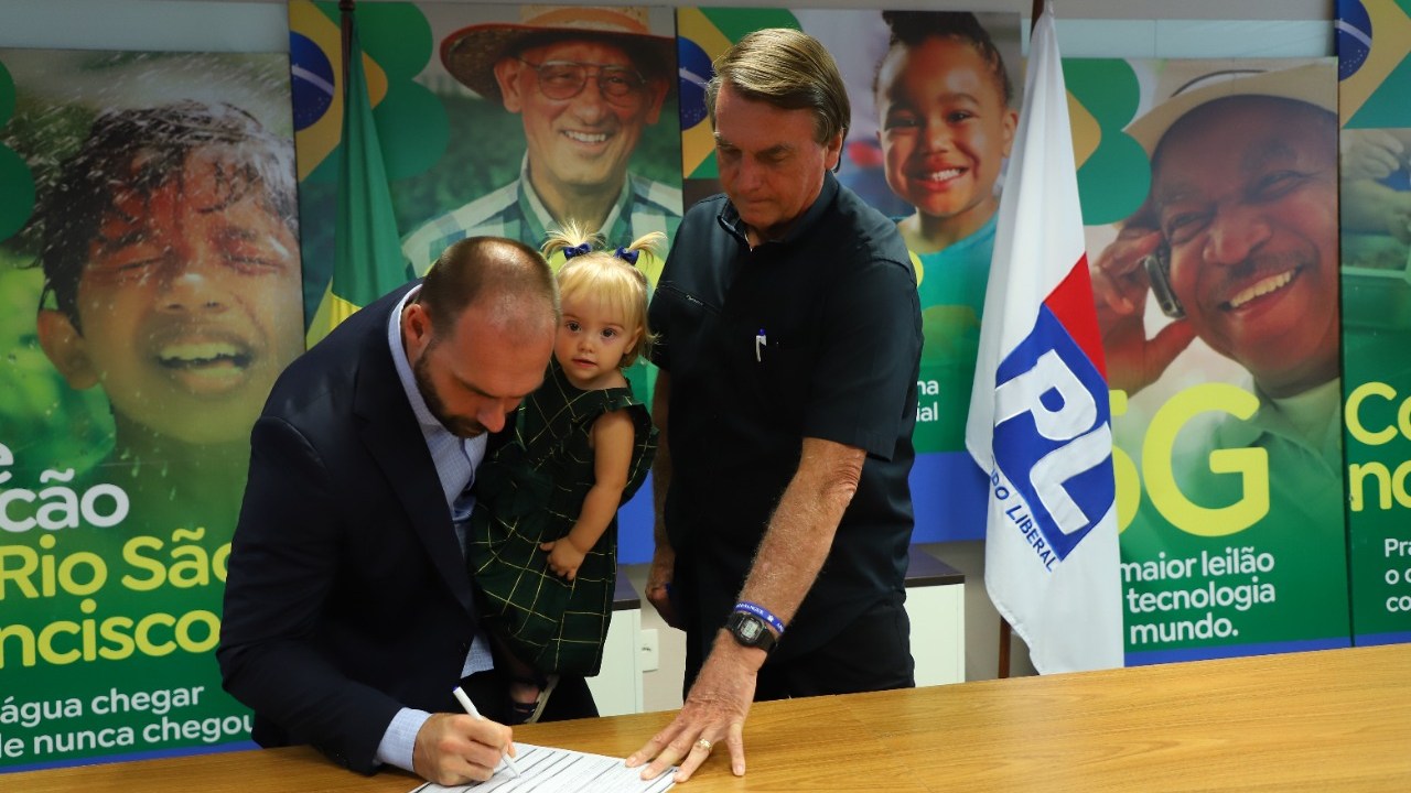 O deputado federal Eduardo Bolsonaro assina ficha de filiação no PL, ao lado do presidente Jair Bolsonaro e com a filha, Geórgia, no colo