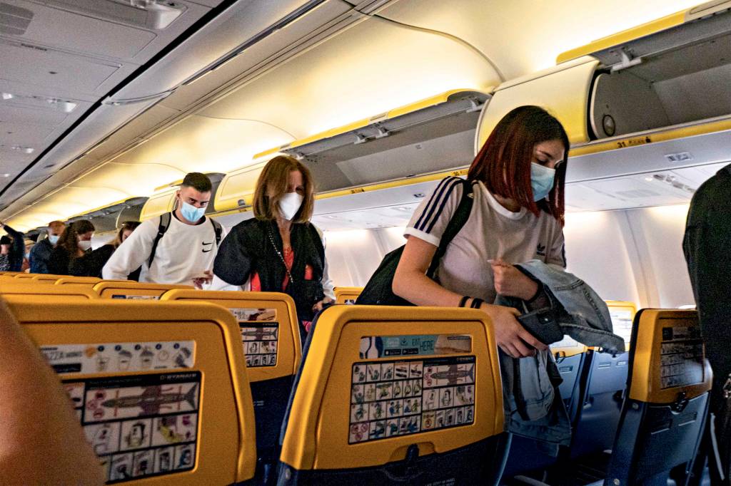 Passengers during the flight wear a facemask in the cabin. Flying during the Covid-19 Coronavirus pandemic inside a Boeing 737-800 aircraft of Ryanair low cost carrier with destination Chania in Crete Island, a popular holiday destination. Inside the airplane is mandatory to wear face masks for the passengers and the flight crew, air stewardess etc while people need a negative COVID test to board on the plane as a safety measure, while the aviation and tourism industry is struggling to return back to normality. Greece is trying to boost its tourism and give privileges to vaccinated against Covid-19 pandemic international tourists and locals, as the country is heavily depended from the tourism industry. Chania Airport, Greece on June 13, 2021 (Photo by Nicolas Economou/NurPhoto via Getty Images)