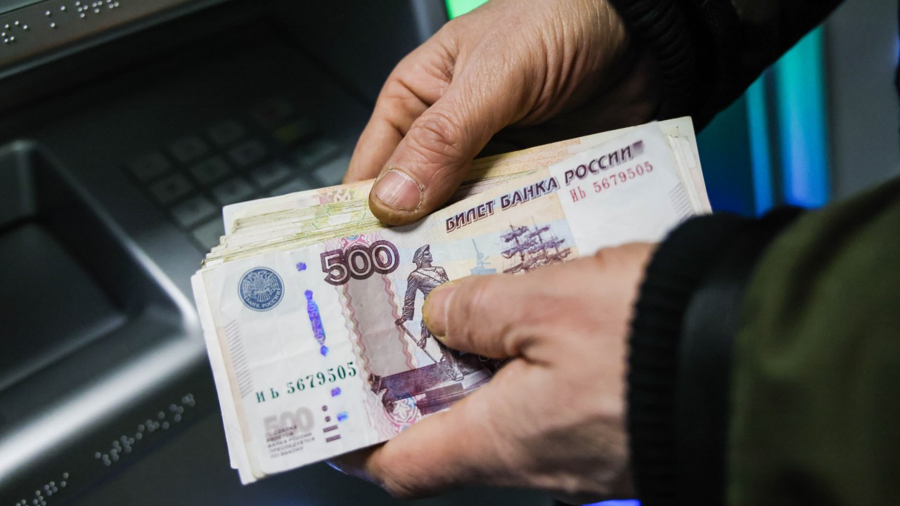 MOSCOW, RUSSIA - FEBRUARY 28, 2022: This image shows a person holding cash withdrawn from an ATM machine at a Sberbank branch. On February 24, the United States announced it was imposing sanctions on major Russian banks, including Sberbank and VTB in response to the special military operation in Ukraine. According to the Sberbank press office, the bank continues to operate normally, with all transactions associated with mortgages and foreign securities available.