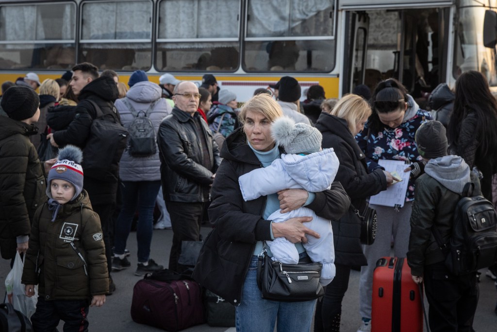 ZAPORIZHZHIA, UKRAINE - MARCH 25: A woman holds a child after getting off a bus that arrived with a large convoy of cars and buses at an evacuation point, carrying hundreds of people evacuated from Mariupol and Melitopol on March 25, 2022 in Zaporizhzhia, Ukraine. Tens of thousands of people remain trapped in Mariupol, a port city that has faced weeks of heavy bombardment by Russian forces. (Photo by /Getty Images)