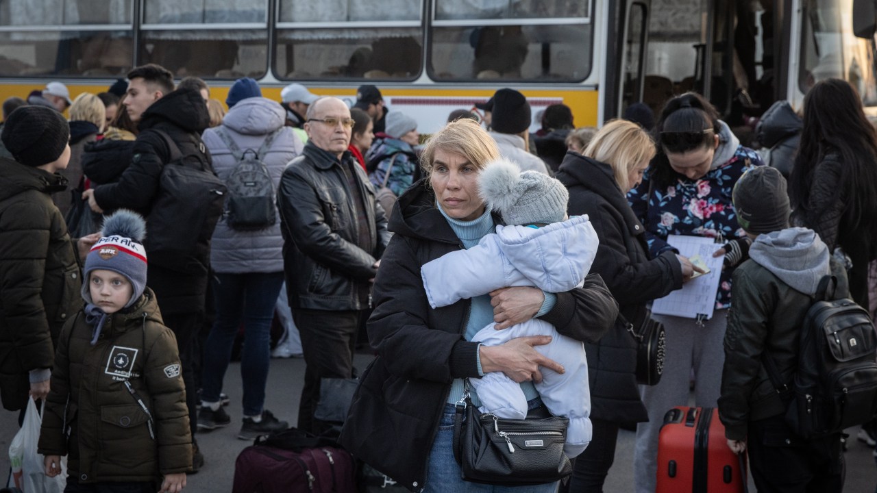 ZAPORIZHZHIA, UKRAINE - MARCH 25: A woman holds a child after getting off a bus that arrived with a large convoy of cars and buses at an evacuation point, carrying hundreds of people evacuated from Mariupol and Melitopol on March 25, 2022 in Zaporizhzhia, Ukraine. Tens of thousands of people remain trapped in Mariupol, a port city that has faced weeks of heavy bombardment by Russian forces. (Photo by /Getty Images)