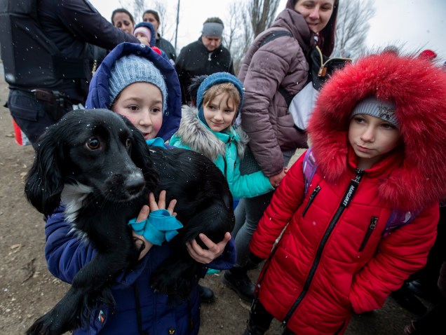 Uma menina segura um cachorro enquanto ela e outros fugindo da Ucrânia passam pela fronteira em Palanca Village, Moldávia -