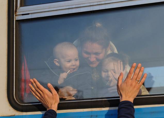 Refugiados ucranianos se despedem enquanto se preparam para partir para a Polônia na estação ferroviária de Lviv, no oeste da Ucrânia -