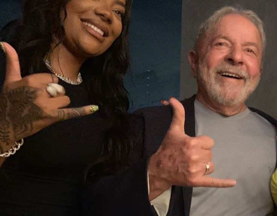 A cantora Ludmilla e o ex-presidente Lula fazem um gesto com as mãos