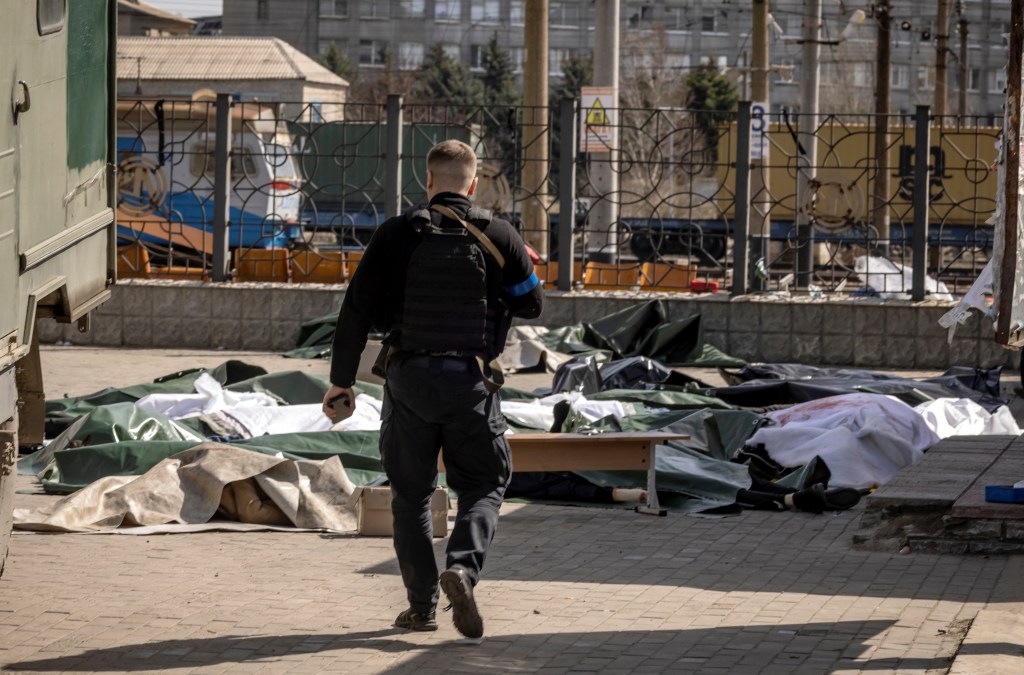 Policial ucraniano anda perto de corpos depois de ataque contra estação de trem em Kramatorsk, Ucrânia. 08/04/2022