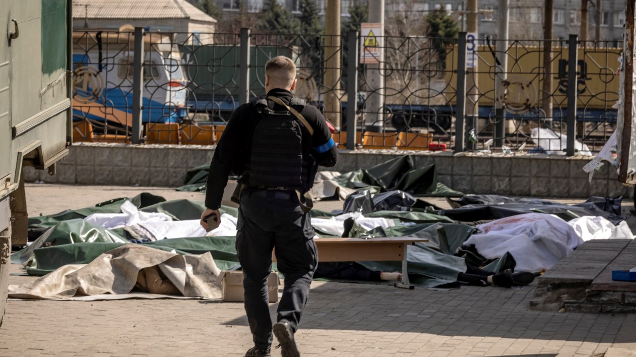 Policial ucraniano anda perto de corpos depois de ataque contra estação de trem em Kramatorsk, Ucrânia. 08/04/2022