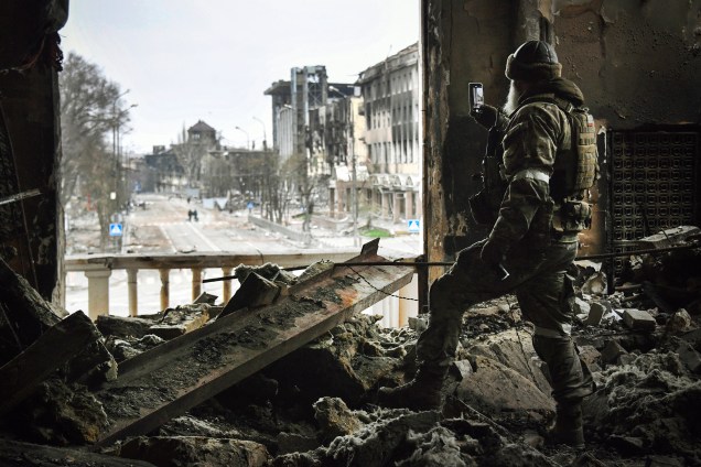 Um soldado russo patrulha o teatro dramático de Mariupol, bombardeado em 16 de março passado, em 12 de abril de 2022. -