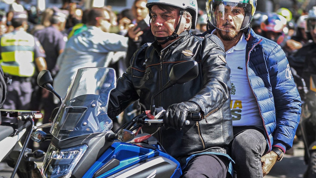Brazilian President Jair Bolsonaro (L) leads a motorcade rally with his supporters in Sao Paulo, Brazil, on April 15, 2022. (Photo by FILIPE ARAUJO / AFP)