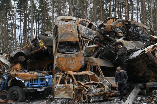 Um homem passa por carros destruídos e queimados em Irpin em 19 de abril de 2022, durante a invasão russa da Ucrânia. -