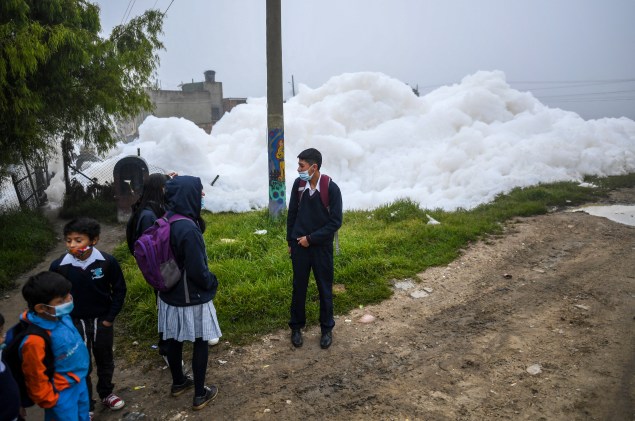 Alunos de uma escola em Mosquera ficam perto de espuma gigante que invadiu o bairro de Los Puentes, em Mosquera, a oeste de Bogotá, em 26 de abril de 2022.