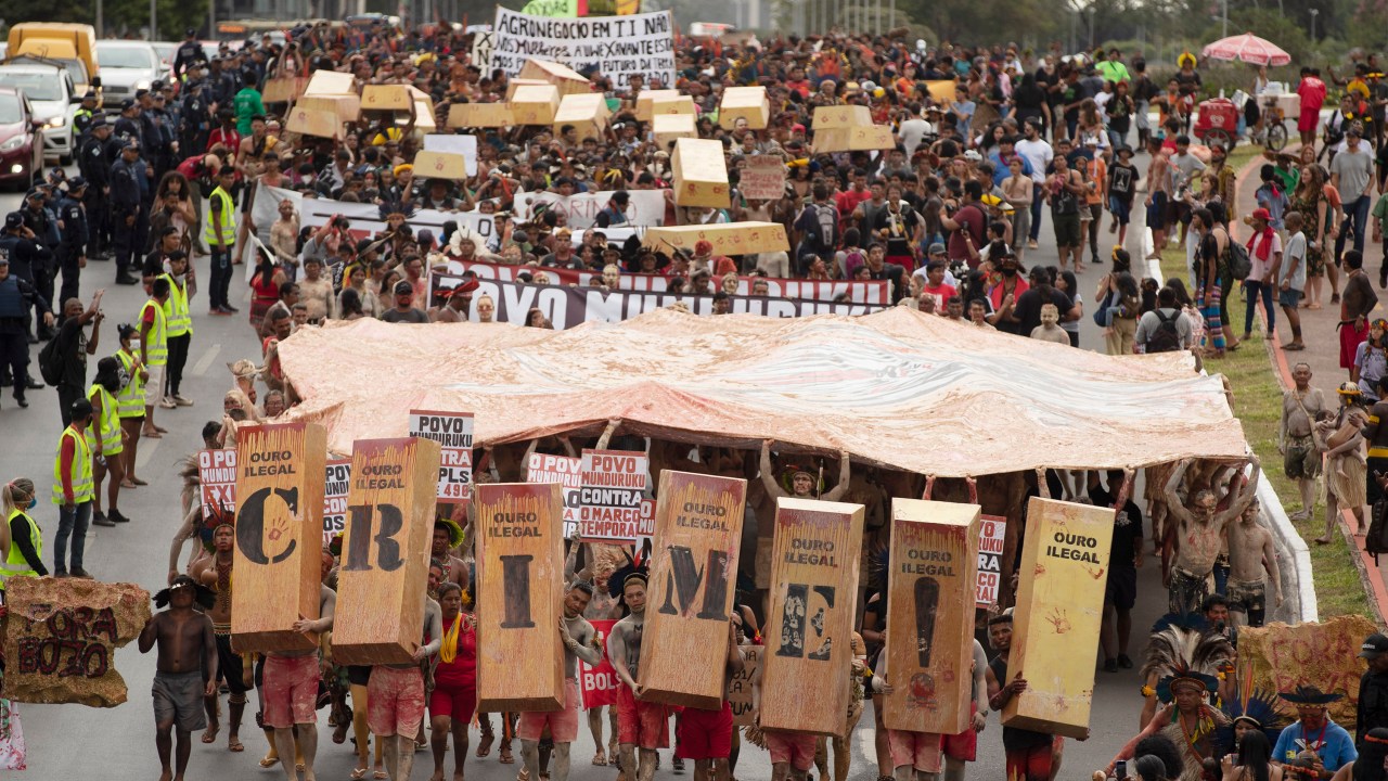 AME565. BRASILIA (BRASIL), 11/04/2022.- Cientos de indígenas de varios pueblos reunidos en el Campamento Tierra Libre (ATL), protestan durante un acto llamado "Ouro de Sangue" (Oro de Sangre) en contra del incremento de la minería en territorios indígenas, hoy, en Brasilia (Brasil). La ATL se realiza en momentos en que el Congreso Nacional y el Gobierno Federal están votando proyectos que violan los derechos de los pueblos indígenas, como el Proyecto de Ley 191/2020. EFE/ Joédson Alves