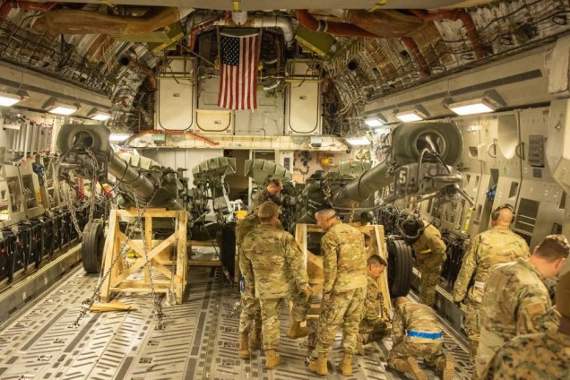 Fuzileiros Navais dos EUA carregando um obus M777 rebocado de 155 mm no porão de carga de um C-17 Globemaster III da Força Aérea dos EUA na Base Aérea de March, Califórnia, em 21 de abril de 2022.