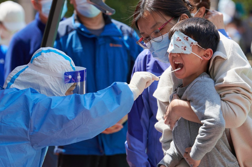 Uma criança recebe um teste de swab para o coronavírus Covid-19 em um complexo durante um bloqueio Covid-19 no distrito de Pudong, em Xangai, em 17 de abril de 2022. (Foto de LIU JIN / AFP) / China OUT