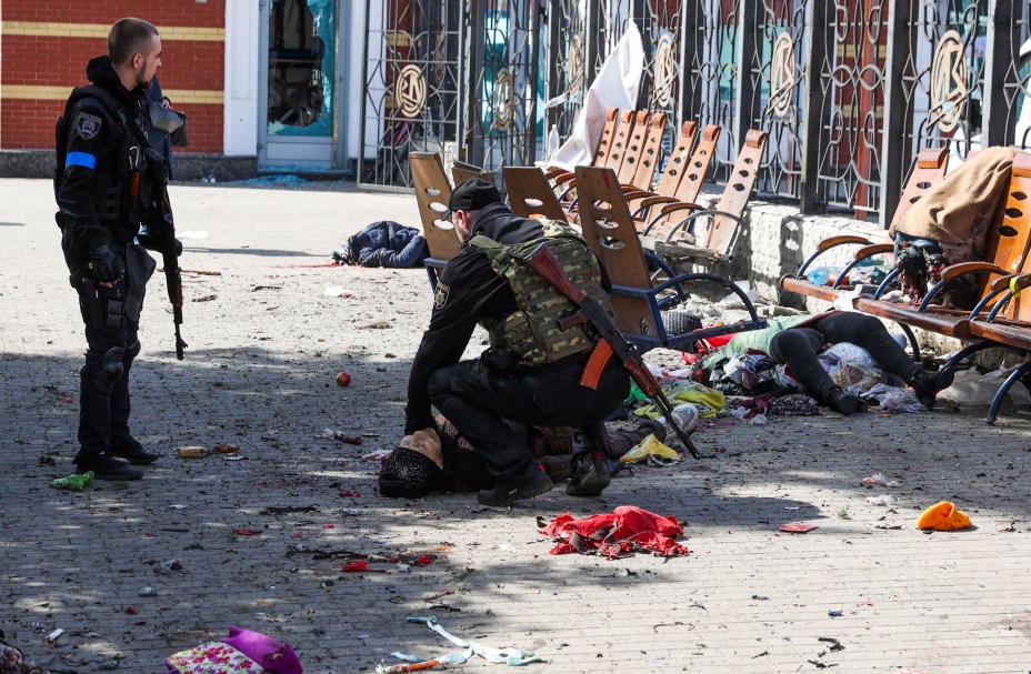 Homens do serviço ucraniano verificam sinais de vida entre vítimas deitadas na plataforma após um ataque russo, na estação ferroviária na cidade oriental de Kramatorsk, na região de Donbass, em 8 de abril de 2022. - Mais Mais de 30 pessoas morreram e mais de 100 ficaram feridas.