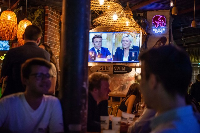 Clientes lotam bares e restaurantes enquanto o presidente francês e candidato à reeleição, Emmanuel Macron e a candidata presidencial Marine Le Pen debatem na TV francesa, em Paris, em 20 de abril de 2022. 