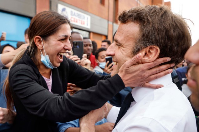 O presidente francês e candidato`a reeleição, Emmanuel Macron, cumprimenta uma moradora do bairro "Fontaine d'Ouche" em Dijon.