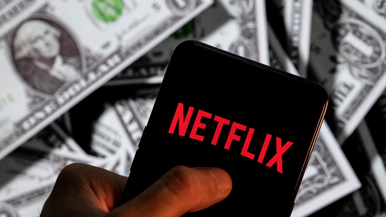 CHINA - 2021/04/23: In this photo illustration, a Netflix logo seen displayed on a smartphone with USD (United States dollar) currency in the background. (Photo Illustration by Budrul Chukrut/SOPA Images/LightRocket via Getty Images)