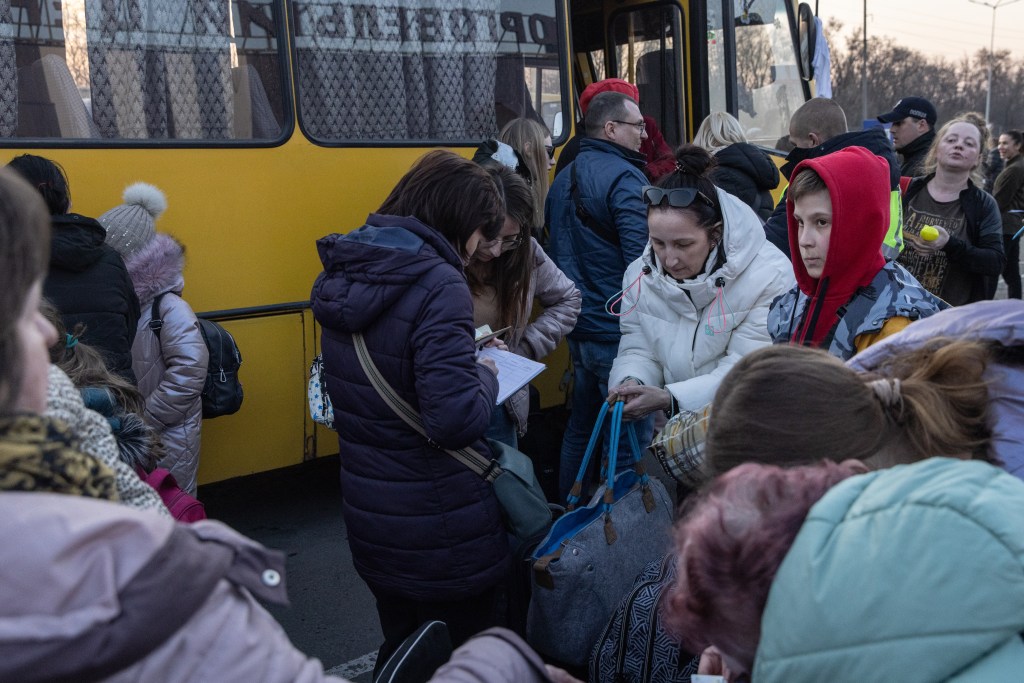 ZAPORIZHZHIA, UKRAINE - MARCH 25: People collect their belongings after getting off a bus that arrived with a large convoy of cars and buses at an evacuation point, carrying hundreds of people evacuated from Mariupol and Melitopol on March 25, 2022 in Zaporizhzhia, Ukraine. Tens of thousands of people remain trapped in Mariupol, a port city that has faced weeks of heavy bombardment by Russian forces. (Photo by Chris McGrath/Getty Images)