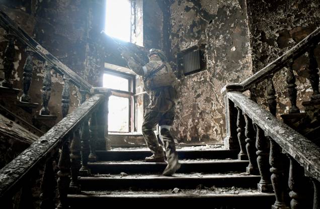 Um soldado russo sobe escadas no teatro de drama de Mariupol, atingido em 16 de março por um ataque aéreo.