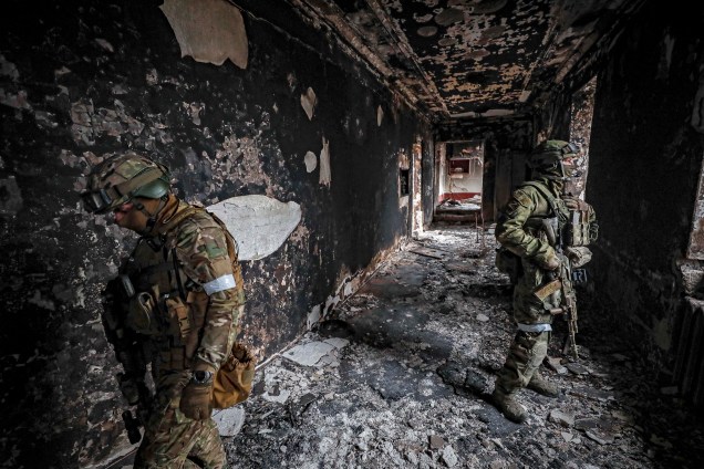 Soldados russos em escombros de prédio em Mariupol, Ucrânia, 12 de abril de 2022.