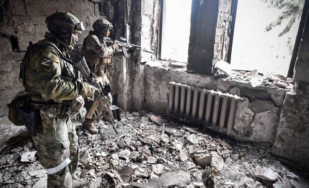 Soldados russos, patrulham prédio bombardeado em Mariupol em 12 de abril de 2022.