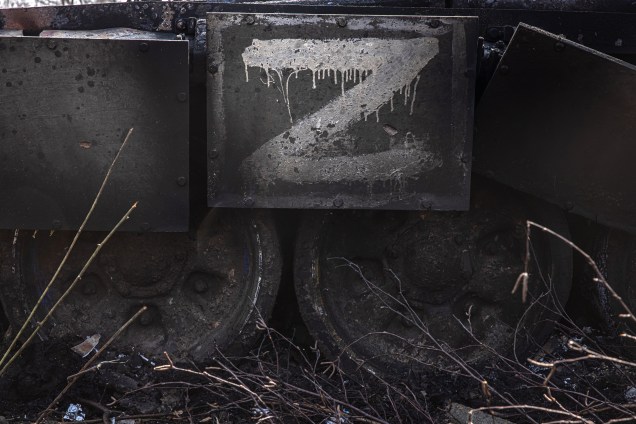Um tanque russo destruído, com a letra "Z", símbolo da invasão russa, ao lado de casas danificadas na aldeia recapturada pelo exército ucraniano Mala Rohan, próximo de Kharkiv, nordeste da Ucrânia , 31 de março de 2022.