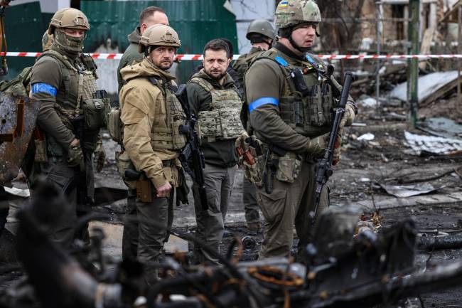 President Volodymyr Zelensky (C) walks in the town of Bucha, just northwest of the Ukrainian capital Kyiv on April 4, 2022. - Ukraine's President Volodymyr Zelensky said on April 3, 2022 the Russian leadership was responsible for civilian killings in Bucha, outside Kyiv, where bodies were found lying in the street after the town was retaken by the Ukrainian army. (Photo by RONALDO SCHEMIDT / AFP)