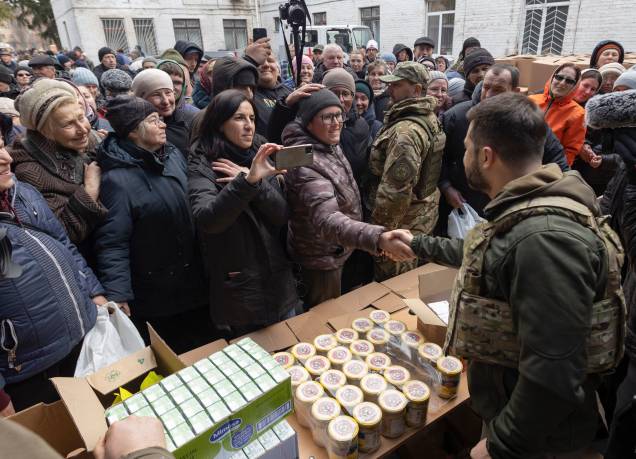 O presidente ucraniano Volodymyr Zelensky conversando com os moradores locais enquanto eles recebem ajuda humanitária -