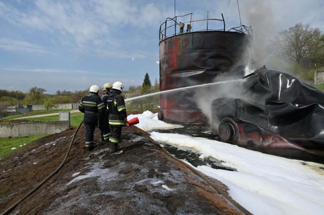 Bombeiros trabalhando para apagar um incêndio em um depósito de petróleo, próximo de Chuguiv, região de Kharkiv, após ataques de mísseis russos em 22 de abril de 2022, em meio à invasão russa da Ucrânia.