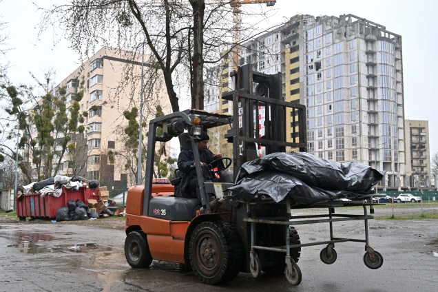 Uma empilhadeiras são utilizadas para remoção dos corpos exumados de um caminhão refrigerado em um necrotério em Bucha, noroeste de Kiev, em 22 de abril de 2022.