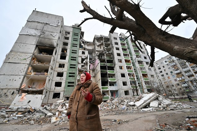 Uma mulher em frente a um prédio de apartamentos destruídos em Chernigiv -