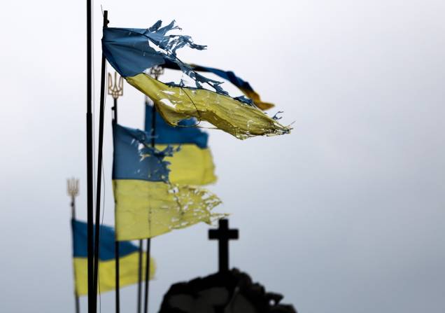 Bandeiras nacionais danificadas tremulam ao vento em um cemitério da cidade de Chernihiv que foi bloqueada por muito tempo pelas tropas russas -